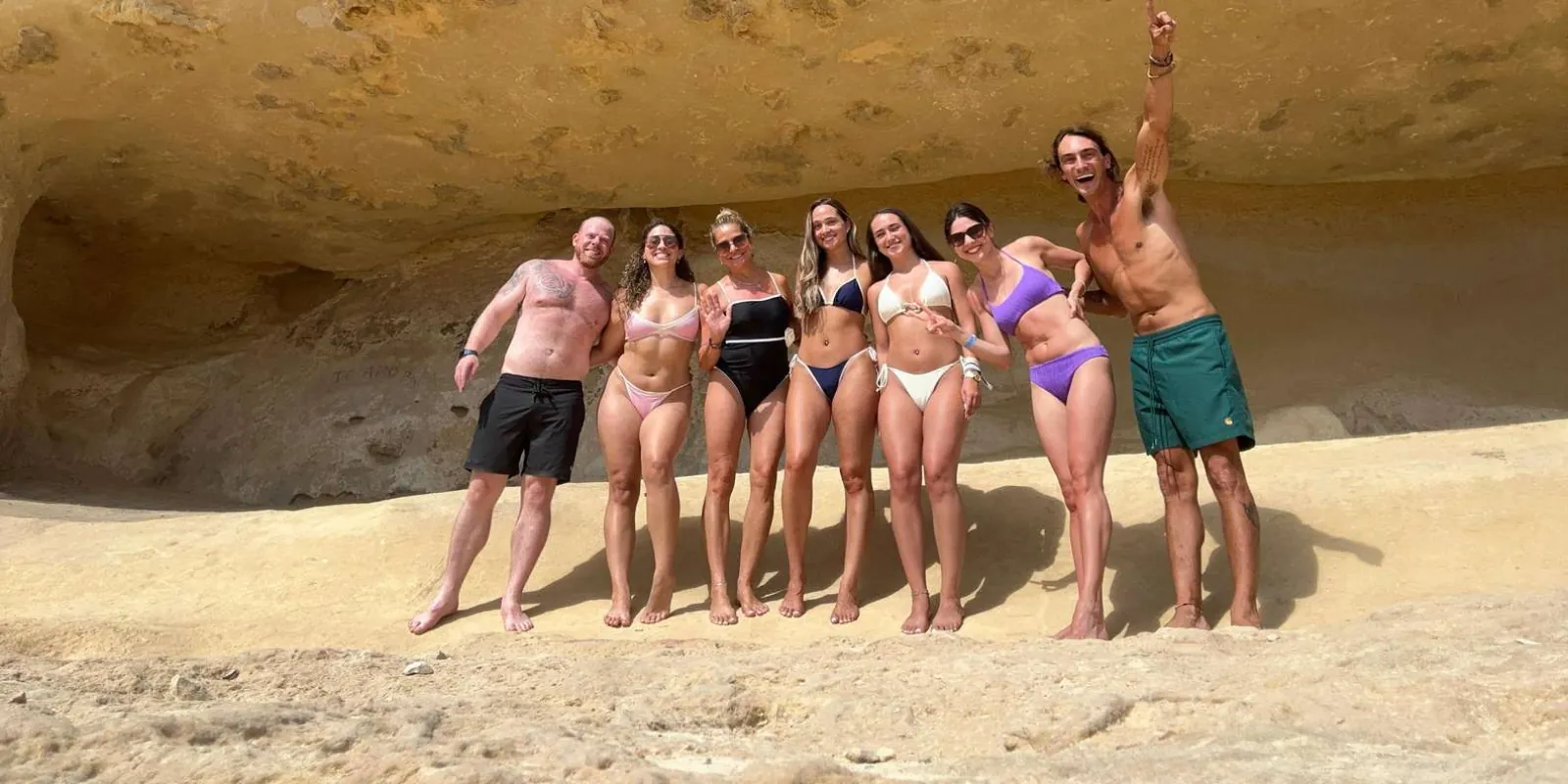 Small VIP group of seven guests posing on a sandy cave beach on the Mallorca coast