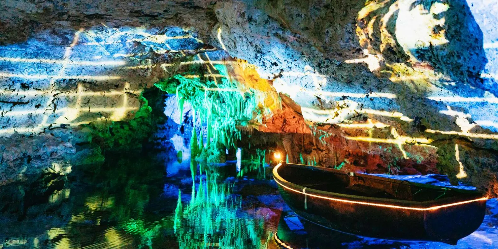 Caves of Drach Lake Martel with colourful light reflections and wooden boats moored at the shore — Mallorca