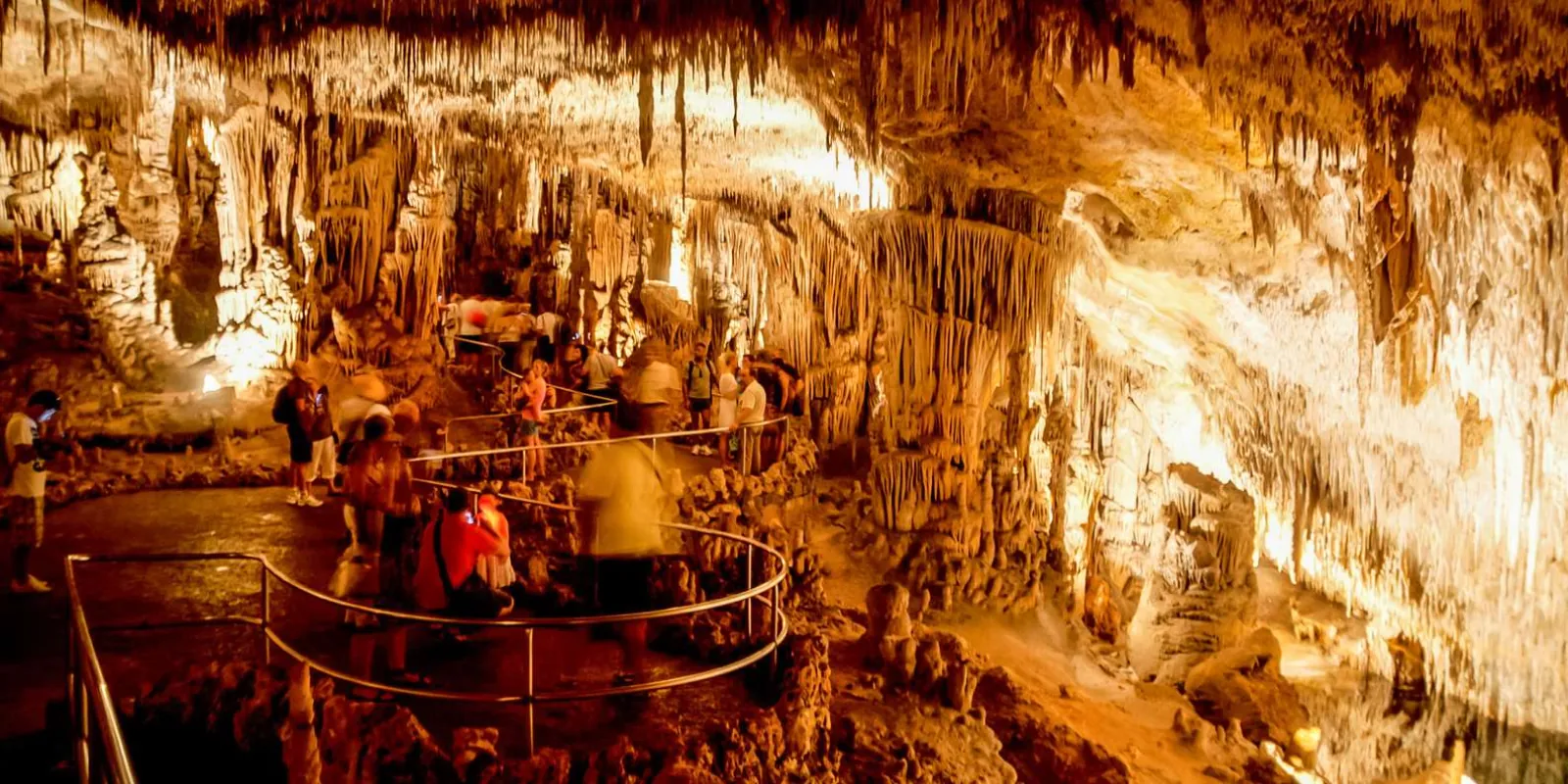 Caves of Drach large chamber with visitors gathered on the railed walkway among stalactites — Mallorca